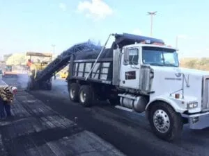 Asphalt Milling Machine Dropping Asphalt into The Bed of a Work Truck