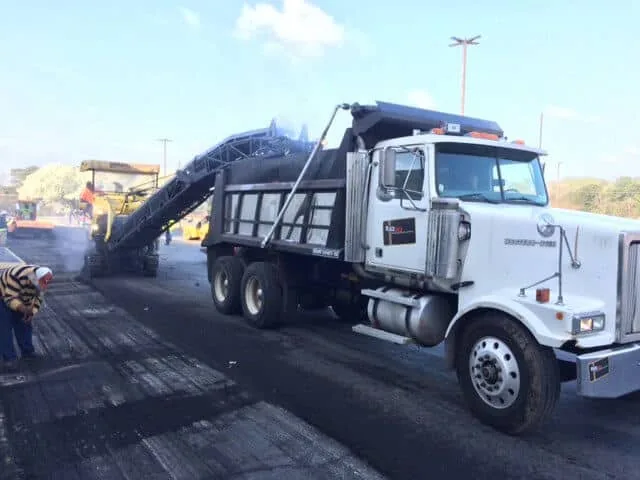 Asphalt Milling Machine Dropping Asphalt into The Bed of a Work Truck