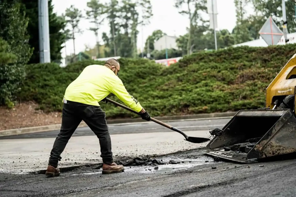Contractor using a shovel to scoop up asphalt